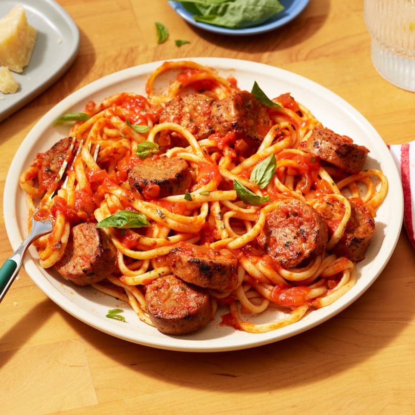Sofiabella Pizzeria's linguine pasta with tomato sauce, sausage, and fresh basil on a white plate.