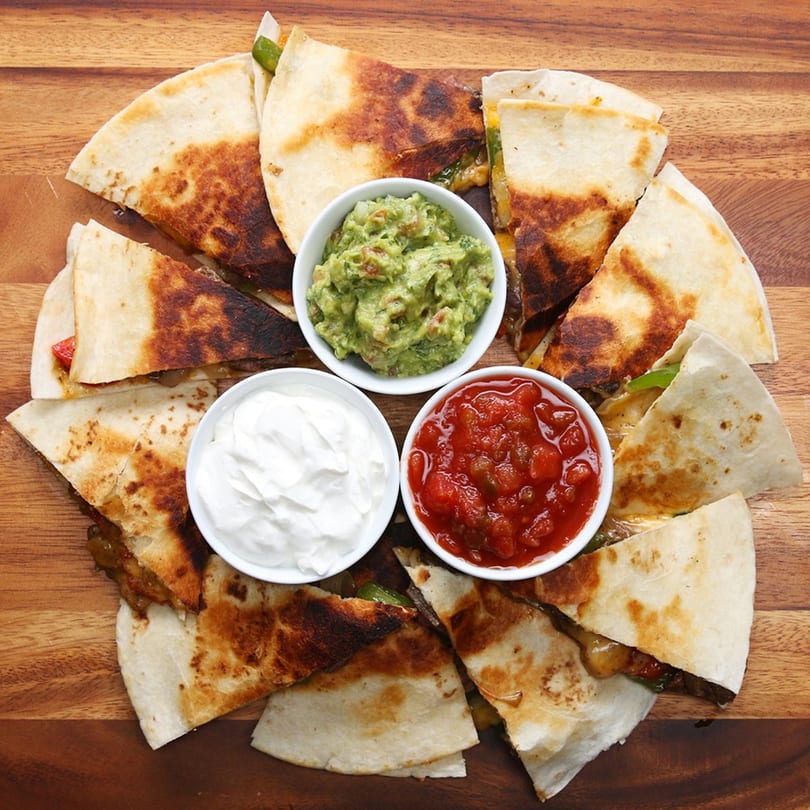 Sofiabella Pizzeria's quesadillas with guacamole, sour cream, and salsa on a wooden board.